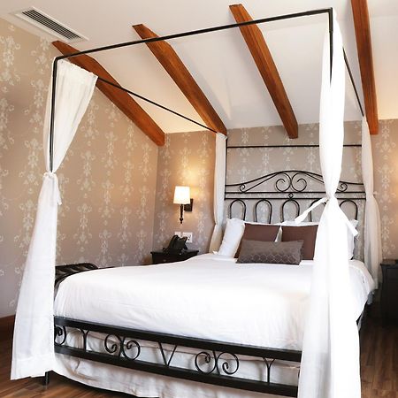 Buona Vitta Gramado Resort & Spa By Gramado Parks Zewnętrze zdjęcie The photo shows a beautifully designed bedroom featuring a four-poster bed with a metal frame and flowing white curtains. The bed is adorned with white bedding and brown decorative pillows. The room has wooden beams on the ceiling and is decorated wi