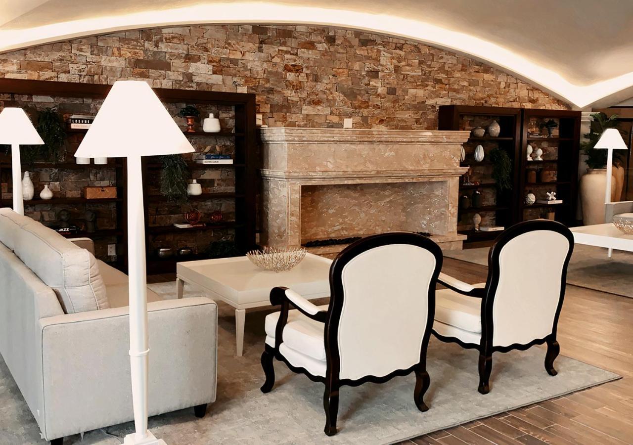 Buona Vitta Gramado Resort & Spa By Gramado Parks Zewnętrze zdjęcie The photo shows a stylish living room with a modern design. In the center, there is a light-colored sofa and two elegant white armchairs with black wooden frames. A coffee table is placed in front of the sofa. Behind them, there is a large, decorativ