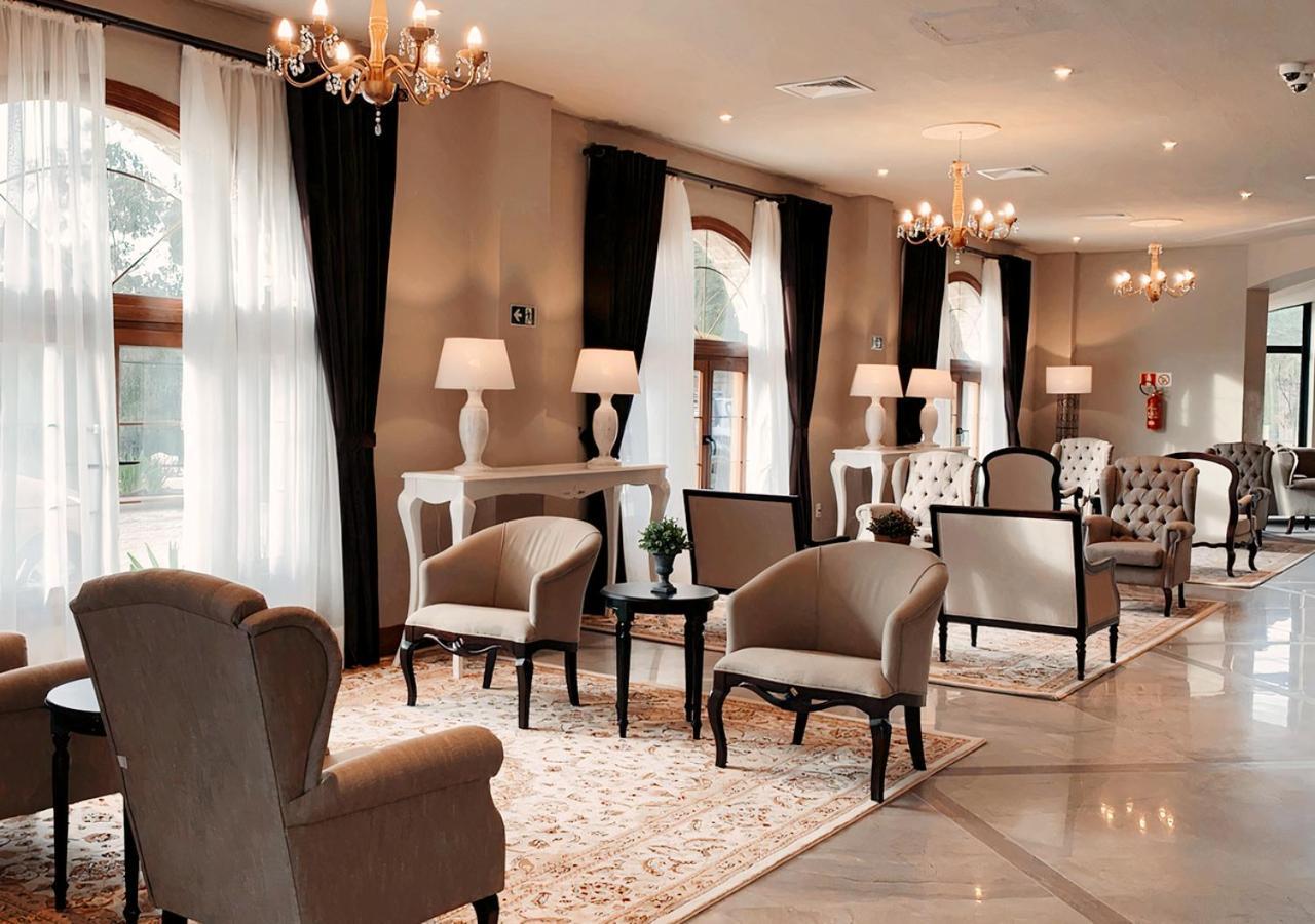 Buona Vitta Gramado Resort & Spa By Gramado Parks Zewnętrze zdjęcie The photo depicts a stylish and sophisticated lounge area. It features several elegant chairs and sofas, arranged around small tables on a decorative rug. The room is well-lit with natural light coming in through large windows dressed with flowing wh