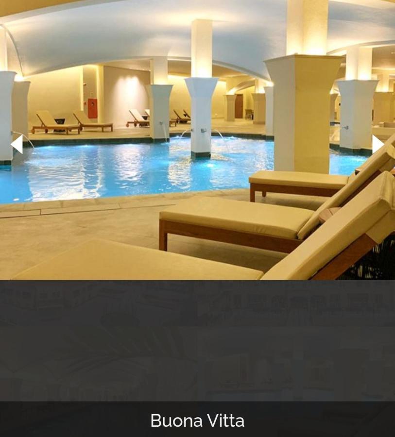Buona Vitta Gramado Resort & Spa By Gramado Parks Zewnętrze zdjęcie The photo shows a tranquil indoor pool area, featuring a large swimming pool with clear blue water. Surrounding the pool are several lounge chairs made of light-colored wood, positioned for relaxation. The space is well-lit, with soft lighting highli