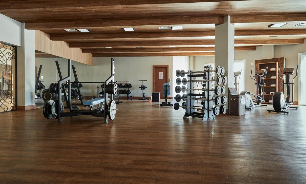 Buona Vitta Gramado Resort & Spa By Gramado Parks Zewnętrze zdjęcie The photo shows a spacious gym with a wooden floor and wooden ceiling beams. Various pieces of gym equipment are visible, including weight benches and racks with weights. On one side, there are free weights organized on a rack, while other equipment 