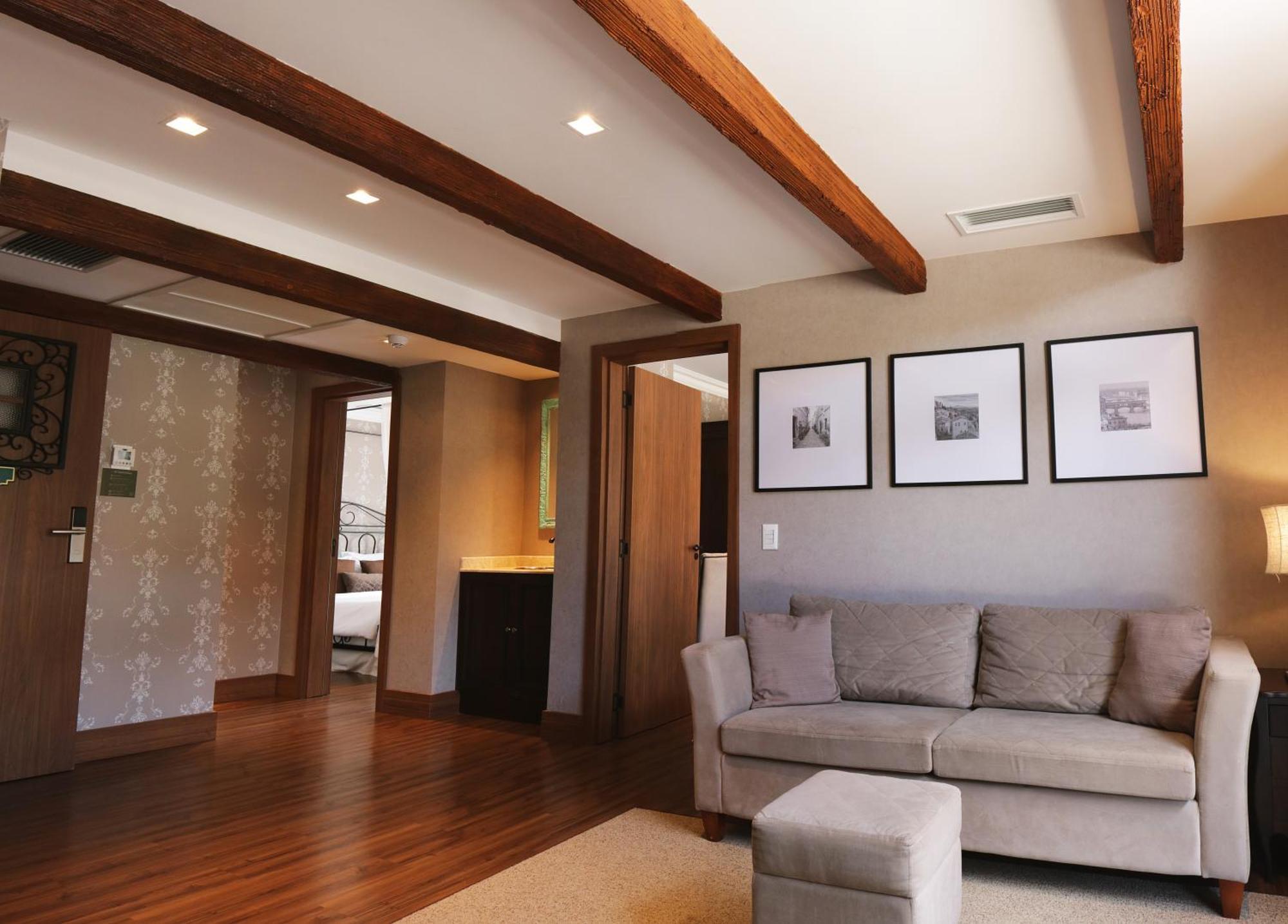 Buona Vitta Gramado Resort & Spa By Gramado Parks Zewnętrze zdjęcie The photo showcases a modern living space with a cozy and well-lit atmosphere. There are wooden beams visible on the ceiling, adding a rustic touch. The flooring is a warm-toned wood, contributing to the inviting feel of the room. 

On one side, ther