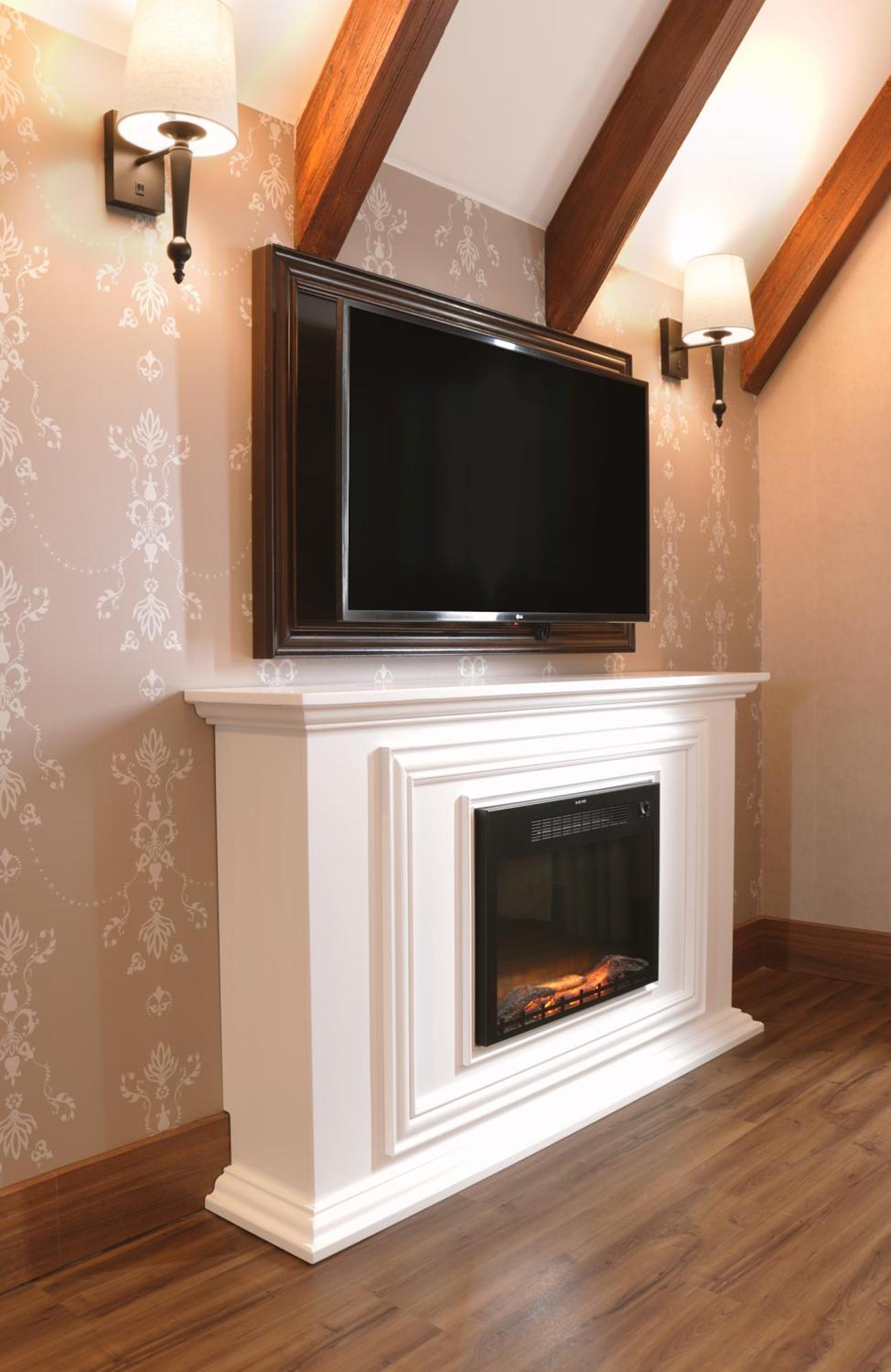 Buona Vitta Gramado Resort & Spa By Gramado Parks Zewnętrze zdjęcie The image shows a modern living room setup featuring a white mantel with an electric fireplace. Above the mantel, there is a large flat-screen television mounted on the wall. The fireplace has a glass front and displays a realistic flame effect, crea